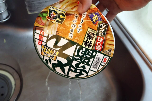 （２）冷やす！　どん兵衛の麺が戻ったら冷水で麺を冷やそう。ザルを使ってもいいが、フタに穴を開けていればカップ焼きそばの要領で湯切りも可能。そのまま麺を冷やすこともできるぞ