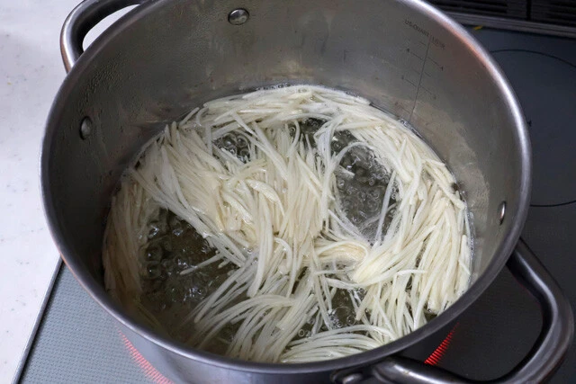 （３）ゆでる！　鍋にお湯を沸騰させ、エノキを入れて1～2分ゆでたらザルにあけ、冷水でしっかり締めてから水気を切る。エノキを結んだ場合は、ゆでている途中でほどけやすいので要注意！