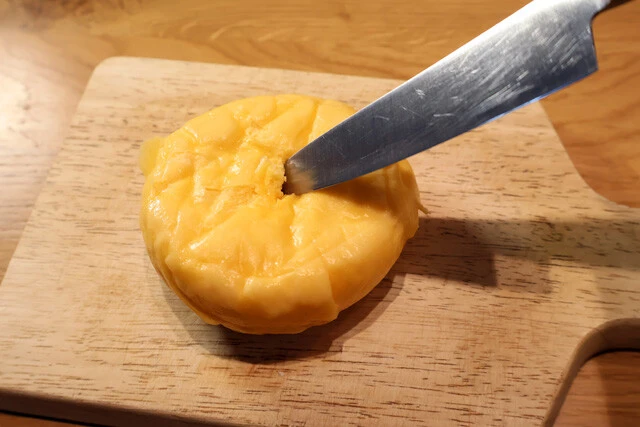 （１）開ける！　コンビニで調達したピザまんの裏面の中央に包丁などで小さな穴を開ける。穴の深さはピザソースの入っているくらいまででOK。後で焼くので冷めた状態でも問題ない