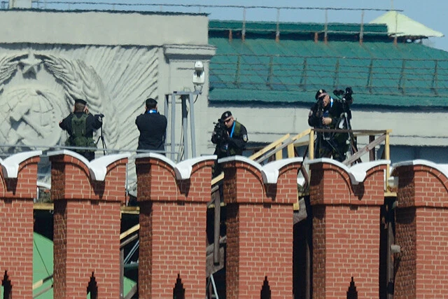 モスクワのホテルから赤の広場のパレードを撮影しようとする柿谷カメラマンを本気で狙うロシア軍狙撃手。２人が同時に狙うことで、命中を確実なものにする