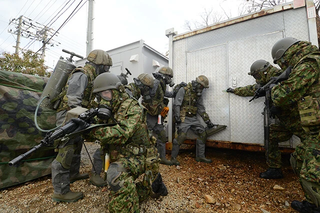 陸自特殊武器防護隊の化学戦装備。先頭の化学陸曹は検知器を持ち、ガスの種類を特定。後方には除染用水タンクを背負った除染班が控える