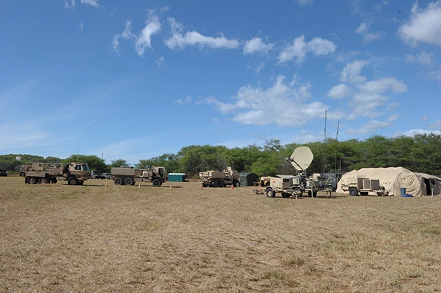 展開する米陸軍地対艦ミサイル部隊。左から３台はミサイル輸送、発射トラック。その右横が通信用アンテナ。天幕内には指揮所がある
