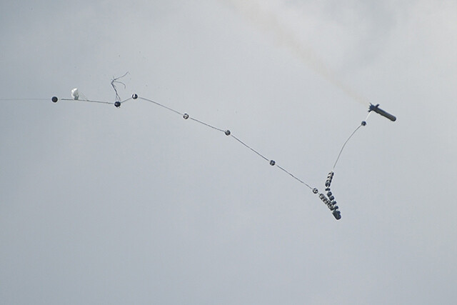 ロケットは爆薬を多数つけたロープを出しながら飛翔する（写真：柿谷哲也）