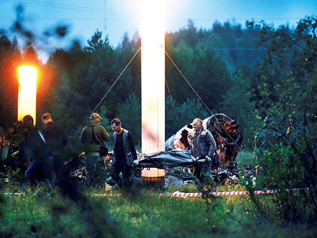 墜落した機体の近くで遺体袋を運ぶ救急隊員（右後方に見えるのは左右どちらかのエンジン）。8000m以上の高度で機外に投げ出された人間の体はバラバラになってしまうというが……