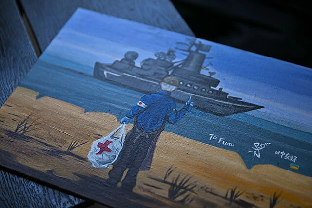 ハルキウでボランティア活動をする中国人アーティストが描いた絵。ウクライナの記念切手のパロディで、ロシア黒海艦隊旗艦に中指を立てる土子さんが描かれている