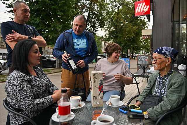 ハルキウ市内のカフェで声をかけられ、日本酒やワインをプレゼントされる土子さん。道行く人に握手や記念撮影を求められることも多い