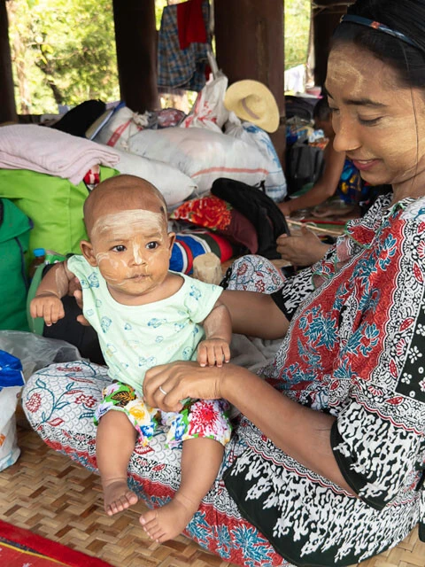 ザヤッ内で赤ちゃんにタナッカー（肌荒れ防止などのために使われるミャンマーの伝統的な白いペイント）を塗る母親