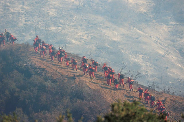 徒歩で火災現場に入る消防士の部隊。空中からの消火活動があるから地上でも消火作業が続けられる