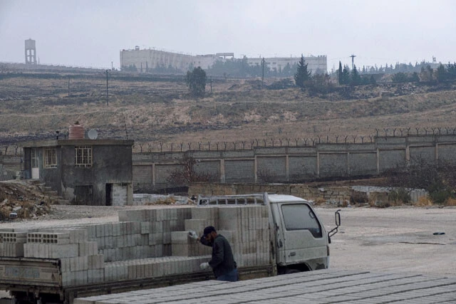 セドナヤ刑務所の外観。写真の「レッドビルディング」と別棟の「ホワイトビルディング」の2棟から成る。付近にはのどかな草原や丘陵が広がっていて、レンガ業者が作業をしていた