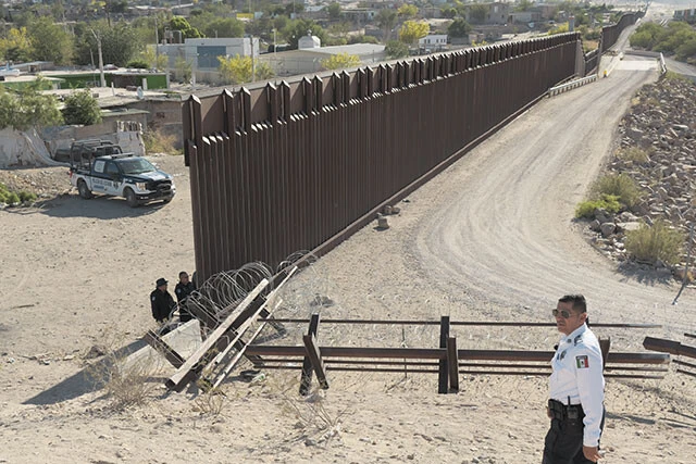 フアレスには、5～6mの国境の壁が途切れ、低い柵だけになる箇所がある。ここはフアレスの中でも最も治安が悪く、後ろに見える住居群の中には、麻薬カルテルの所持する武器や麻薬、そしてカルテルが拉致した若者や移民が隠されているという。手前が警官歴20年超のエドゥアルド氏