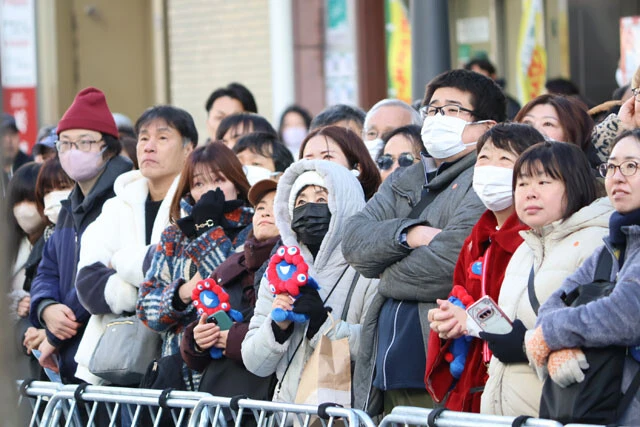 吉村氏の演説を見守る人たち。同氏の支持者であろう人たちの多くが、なぜかミャクミャクの人形を持っていた