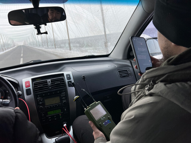 FPVドローンの映像信号を自動的に検知し、追尾を察知する「ディテクター」を持つ男性。クルマで移動する際の必需品だ