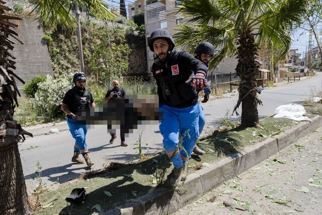 バイクを運転していたところ、イスラエル軍のドローンに爆撃された男性を救助する隊員たち。上空では戦闘機の音が響いていた