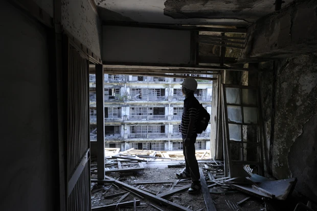 40年以上前に10代を過ごした部屋にたたずむ坂本さん。彼の家族の家は、総戸数300戸以上を誇る軍艦島最大の鉱員住宅だった65号棟(北側)の9階部分にあった