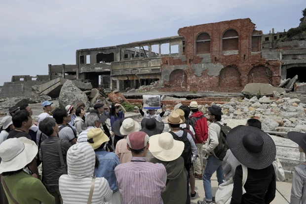 軍艦島に上陸してガイドをする坂本さん(中央)。観光客は全身全霊で話す彼の姿を目の当たりにし、「観光で来ていたことを忘れてしまった」との声も