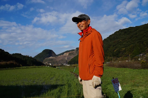 強制収用された自身の田んぼの前に立つ石丸勇さん。今年も「ここは私の田んぼですから」と作付する予定だ