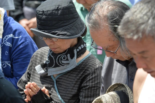 被害女性追悼のため黙とうを捧げる参加者たち