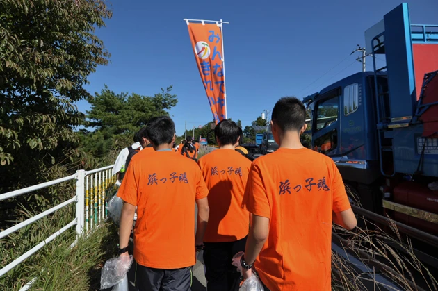 福島の国道６号線の清掃ボランティアには地元の高校生も参加。その清掃エリアには線量が高いスポットも点在していた。放射線量が非常に高いレベルにある帰宅困難区域方面から来たダンプカーが何台も高校生の脇を通りすぎていく…