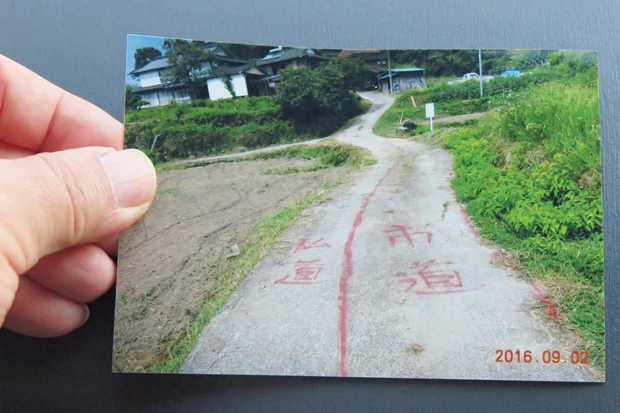 道路の真ん中に一本の線が引かれ、路面には「私道」「市道」と書かれている。「これは私の畑に自宅が隣接しているＢさんが、昨年の９月に書いたものです。私道は私有地だから入るな！ということですね」（Ａさん）