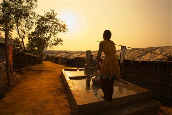 夕刻、井戸水を壺にくむ少女が夕日に光っていた