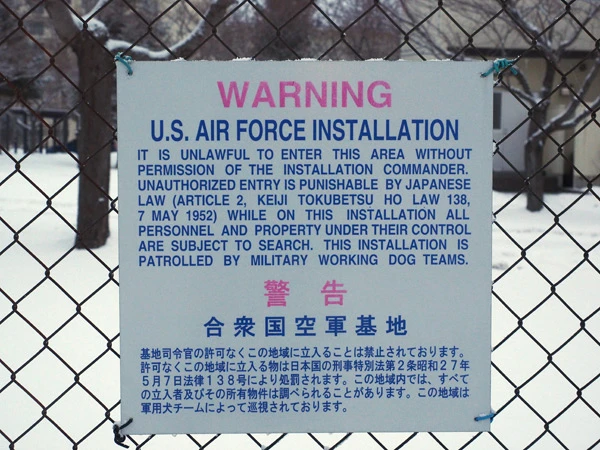 基地との境目に張り巡らされた金網に張られている警告の看板。