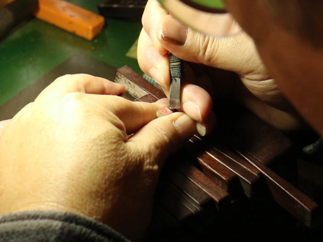 ハンコ作りの作業風景。６㎜角のロウ石に鏡文字で字入れ（筆で書き込み）し、その筆跡に沿って彫っていく。印刀は自分で研いだものを何種類も使い分ける