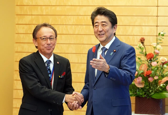 毎年3000億円前後の沖縄振興予算は、近年では沖縄県側の米軍基地問題に対する姿勢により金額が増減する政治案件と化している(左は玉城デニー県知事、右は安倍晋三元首相)