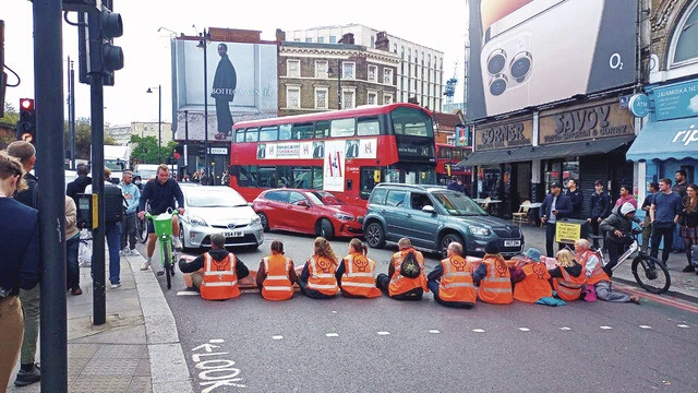 交通量の多い幹線道路に座り込む抗議行動も彼らの定番。自らの体を地面に接着する者も