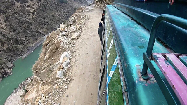 アジアンドキュメンタリーズで配信中の『秘境をぶっ飛ばせ!』より。ハンドル操作を誤れば崖下へ一直線の道で、危険なカーチェイスが繰り広げられる