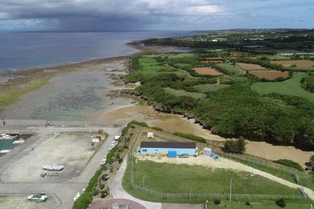 うなぎの完全養殖を目指す新日本科学の研究所(青い建物)は、沖永良部島(鹿児島)の自然に囲まれている