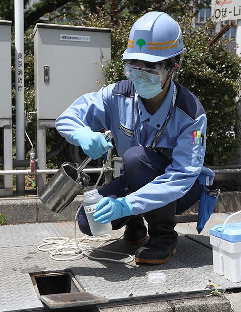 下水中のコロナウイルス量を調べるために、水再生センターの処理水を採取する様子(2020年5月東京都)