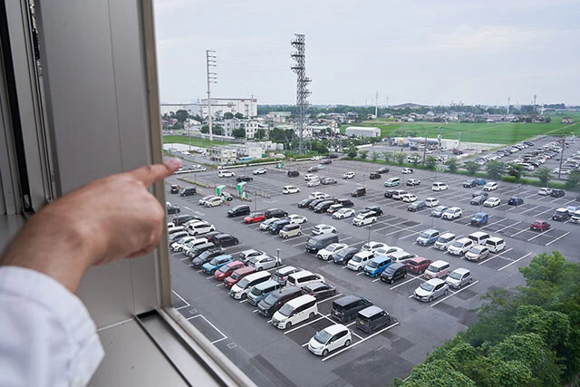 コロナの感染が拡大すると、埼玉医科大学総合医療センターの駐車スペースにはコロナ患者を診るための特別病棟が建てられた。その位置を指さす、現場で指揮し続けた岡教授