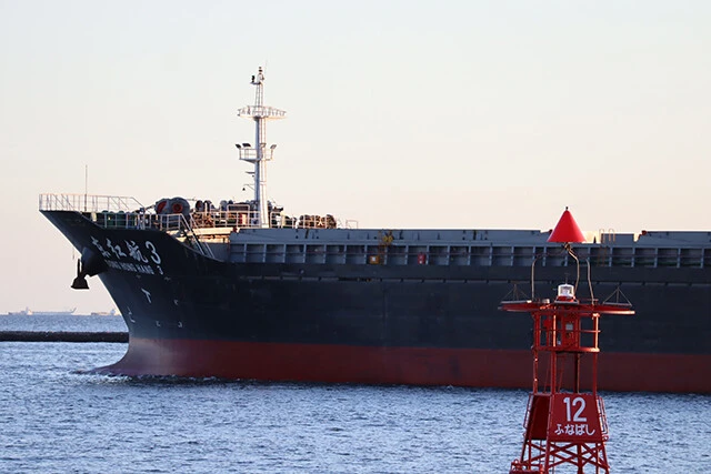 千葉県船橋の港から出港する中国籍の巨大な輸送船。ヤードから直接金属（銅線）を運び入れ、海外に送り出していく