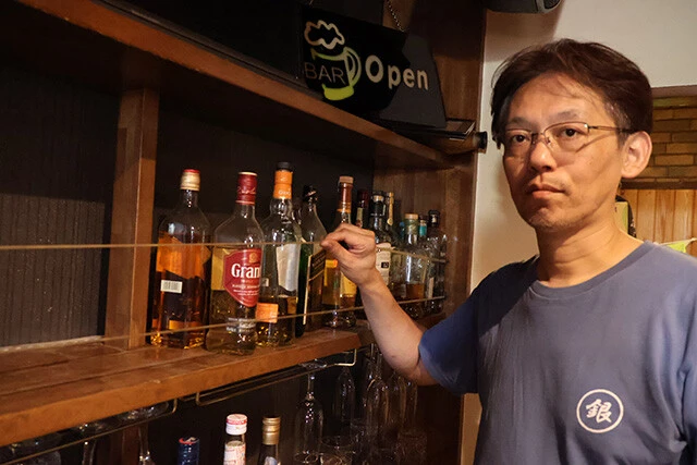 氷川町のバー「エクライザル」のマスター・佐藤敬明さん。2016年の地震の教訓を踏まえ、棚にボトル落下防止のヒモを張っていたが、今回の地震は想定以上の揺れで、ほとんどのボトルが床に落ちてしまったという