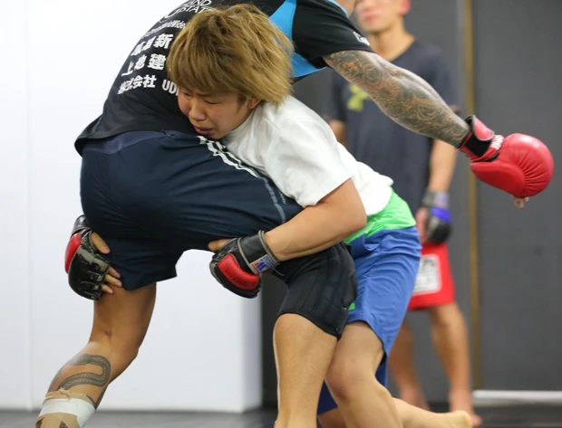 自分よりずっと大きい男性ファイターをタックルでなぎ倒す村田