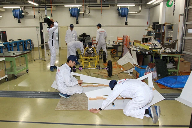 車体の骨格となるパイプフレームは、以前、先輩がつくった学生フォーミュラのマシンから流用し、ボディカウルは「プラダン」(プラスチック製の段ボール)を加工。「重量制限が最大80㎏なのに、現状フレームだけで82㎏なんですよ......。軽量化しないと」と車体担当の生徒さん。カウル部隊はカッターナイフと格闘中!(撮影/川喜田 研)