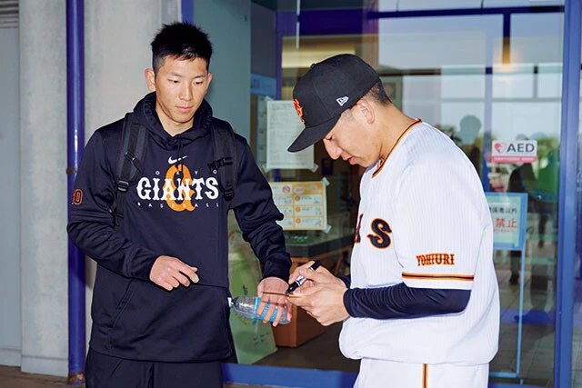 練習後、見学に訪れたチームメイトの戸郷翔征(写真左)の兄に、気さくにサイン対応する姿も