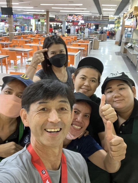 現地のフードコートや屋台で食事をしながら、タイでのコミュニケーションを学んだという石井。店員たちとの写真でも笑顔があふれる