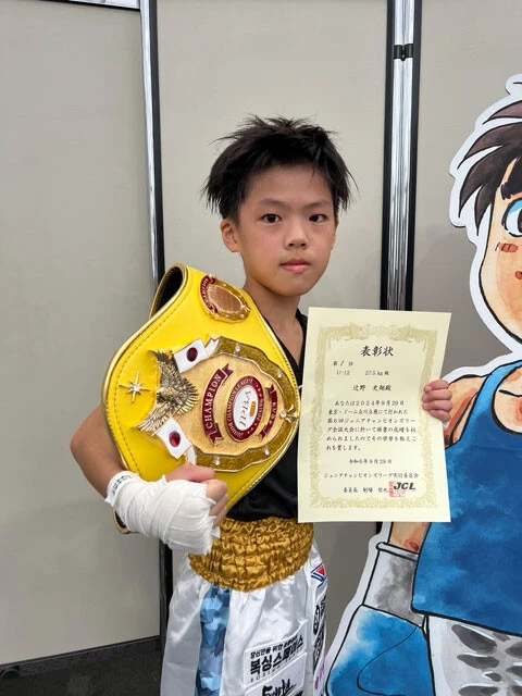 9月29日に開催されたジュニアボクシングの全国大会（第6回ジュニア・チャンピオンズリーグ全国大会決勝戦）に、キッズコースの選手も出場。5年生の辻野史翔(つじのあやと)選手がU-12、27.5kg級で見事優勝し、拳四朗よりひとあし先に、栄光のチャンピオンベルトを手にした。（写真提供／加藤健太トレーナー）