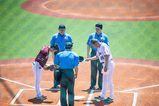 メンバー表を交換する、楽天の渡辺直人2軍監督(左)とヤクルトの池山2軍監督(右)。