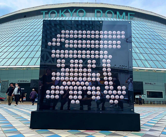 田中のグラブに刺繍されている「氣持ち」の「氣」を200個のボールで表現する、高さ200㎝の「『氣』モニュメント」が開幕戦から東京ドーム22ゲート前広場に展示されている。ボールには1から197までの数字と、勝利した日付、当時の所属球団で背負った番号が印字されており、198個目以降は勝利後に随時追加し、日米通算200勝を達成すると完成するという（写真／読売ジャイアンツ公式X）