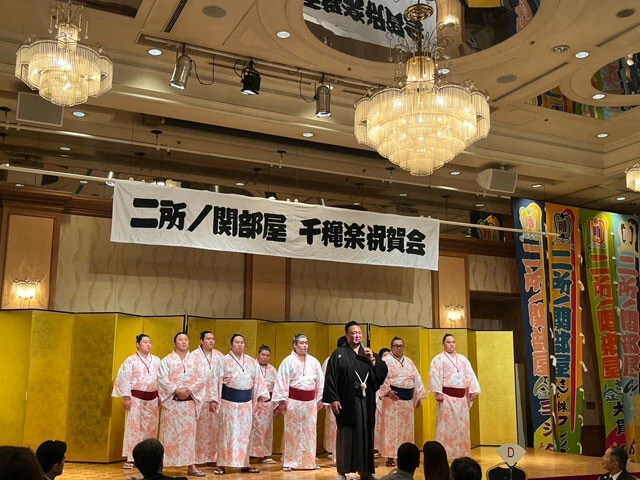 千秋楽祝賀会で支援者に挨拶をする二所ノ関親方。松田はこのときの力士たちと支援者との交流に、昨年のパリ五輪の取材を経て強く意識するようになった「スポーツホスピタリティ」の源流を見た