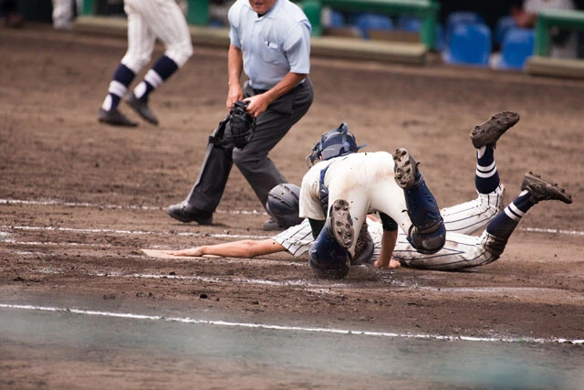 高校野球でホームベースに滑り込む走者のイメージ画像