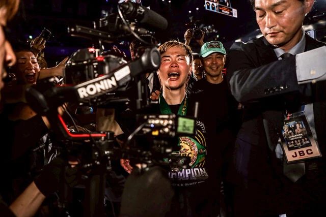 ファンに揉みくちゃにされながら花道を引き上げる天心。キック時代からの蓄積があった葛西裕一トレーナー（右奥）は、喜びを爆発させる愛弟子・天心の会心の勝利に満足げな表情を見せる