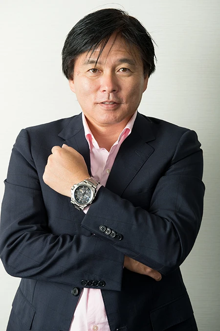 カシオ計算機・時計戦略部プロモーション室長の上間氏。腕に輝くメタルの重厚感ある時計は世界初・GPSハイブリッド電波ソーラーを搭載したMTG-G1000D-1A2JF