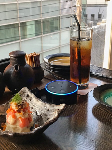 テーブルに置かれたスマートスピーカー「アマゾン・エコー・ドット」(中央)。呼び鈴と変わらないサイズ。