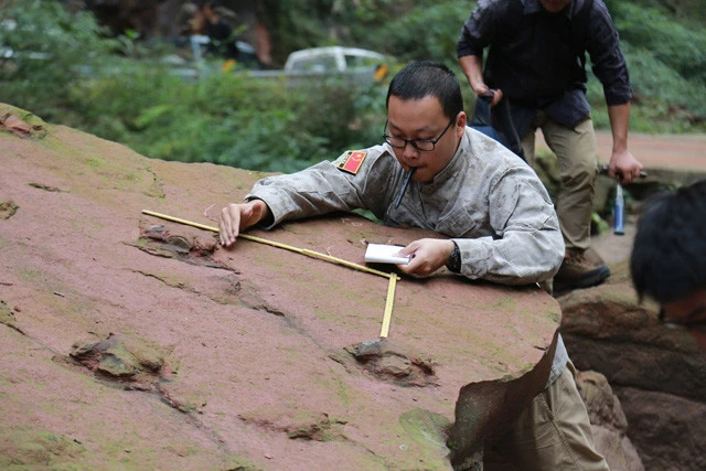 中国四川省の辺境・古藺河の河畔で足跡化石を調査するシン博士。琥珀だけではなく、地層に向き合う昔ながらの発掘も行なっている