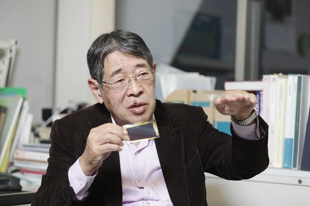 フィルム状の小さいペロブスカイト太陽電池を手に持つ宮坂氏。日本が国際競争から後れを取らないためにも企業は今こそアクセルを思い切り踏むことが重要と語る