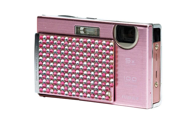 00年代、ガラケーのデコ電をはじめ私物をなんでもラインストーンでデコるデコ文化がギャルを中心に流行し、デジカメにも波及。軽量・小型化のため不要な意匠が排除されたコンデジも一気にキラキラアイテムに！