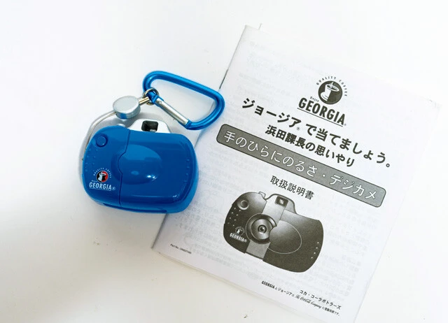 浜田課長の思いやり「手のひらにのるさ・デジカメ」。缶コーヒーのジョージアの懸賞品。Win95用のシリアルケーブルまで付属する思いやり